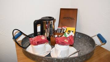A tray with two white cups, a kettle, and a box labeled "TWININGS."