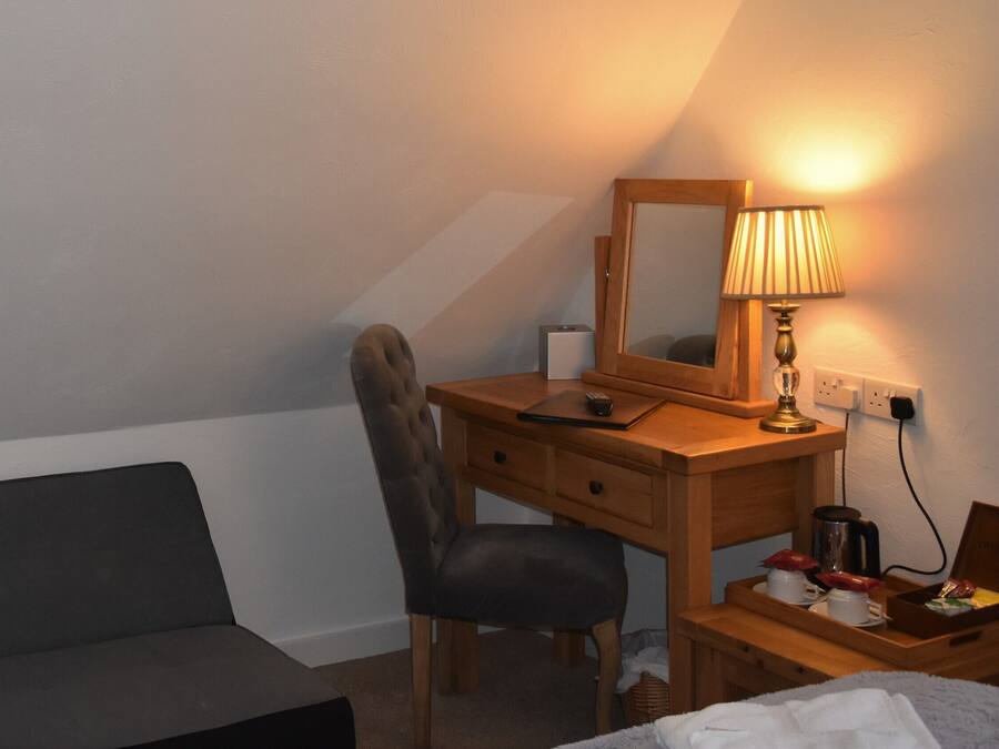Habitación de hotel con cama, escritorio, silla, lámpara y televisor montado en la pared.