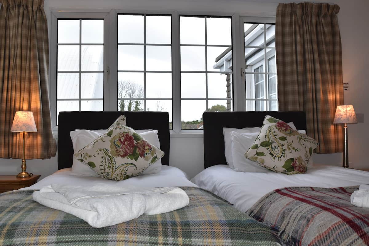 Quarto de hotel com duas camas, uma janela grande e vista para prédios.
