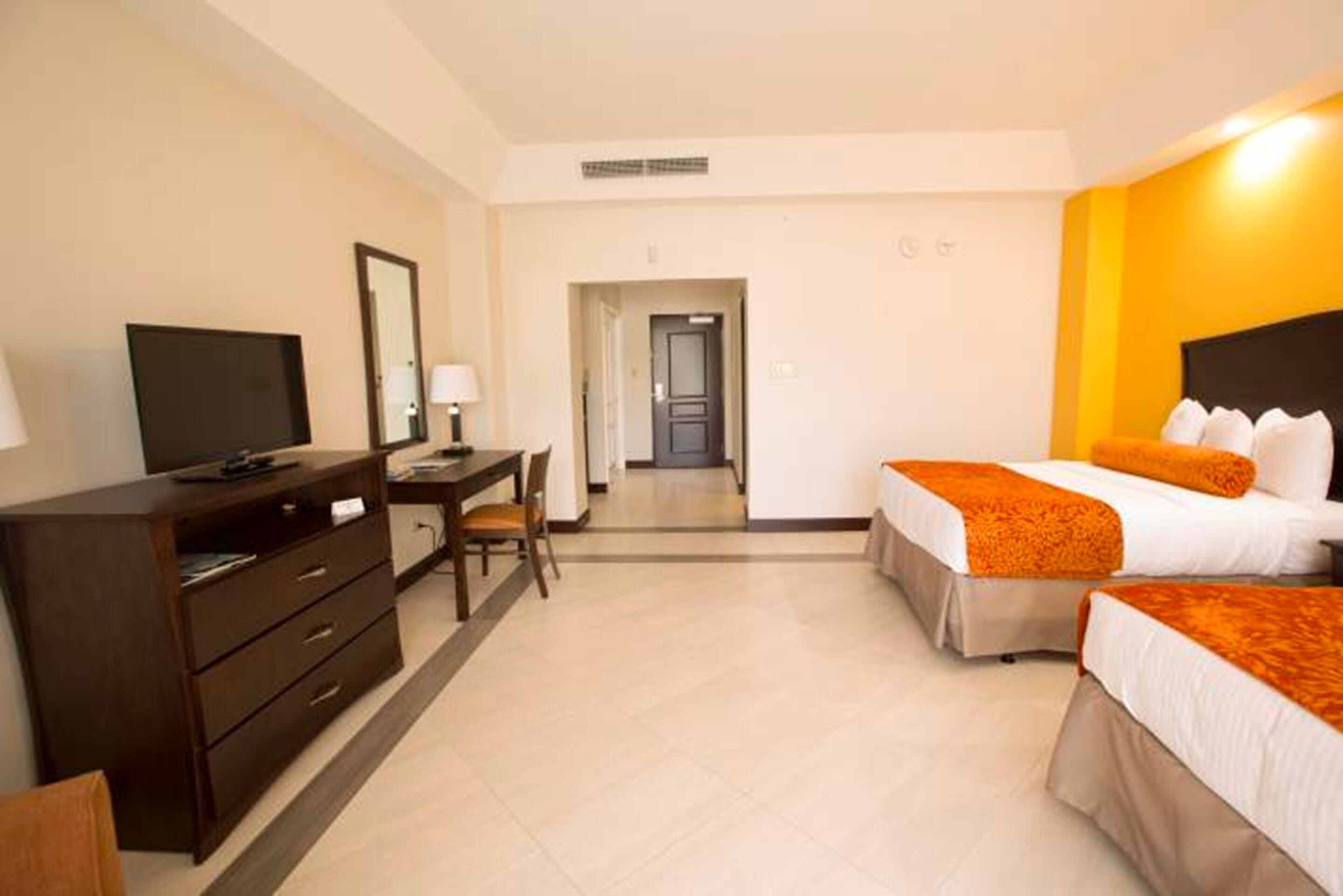 A hotel room with a bed, a desk, a chair, a television, and a wardrobe.