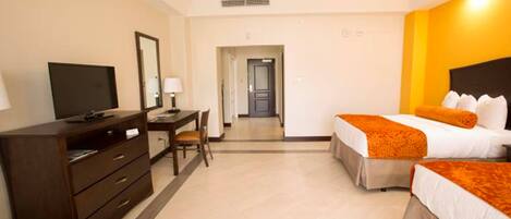 A hotel room with a bed, a desk, a chair, a television, and a wardrobe.