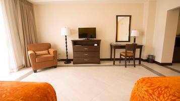 A hotel room with two beds, a TV, a desk, and a chair.