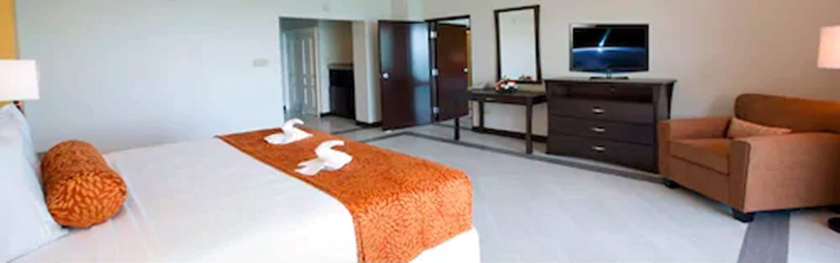 Een hotelkamer met een bed, een bureau, een televisie en een bank.