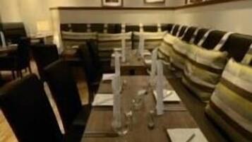 Un comedor con una mesa larga dispuesta para una comida, rodeado de sillas.