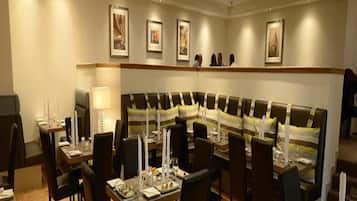 A restaurant with a long dining table, multiple chairs, and a high-backed sofa.