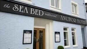 A building with a sign reading "The SEA BED Restaurant" and "ANCHOR HOTEL".