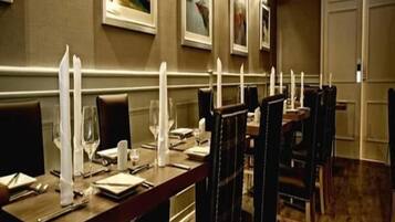 Un comedor con mesas dispuestas para el servicio, sillas y cuadros en las paredes.