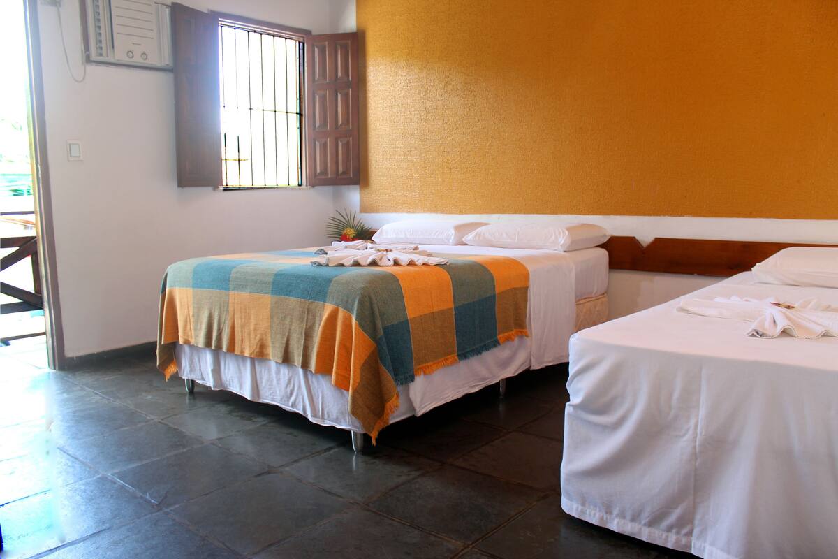 A hotel room with two beds, a window with bars, and a tiled floor.