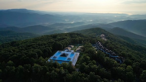 A resort with a swimming pool, surrounded by dense forest and mountains. - Art of Living Retreat Center (Boone)