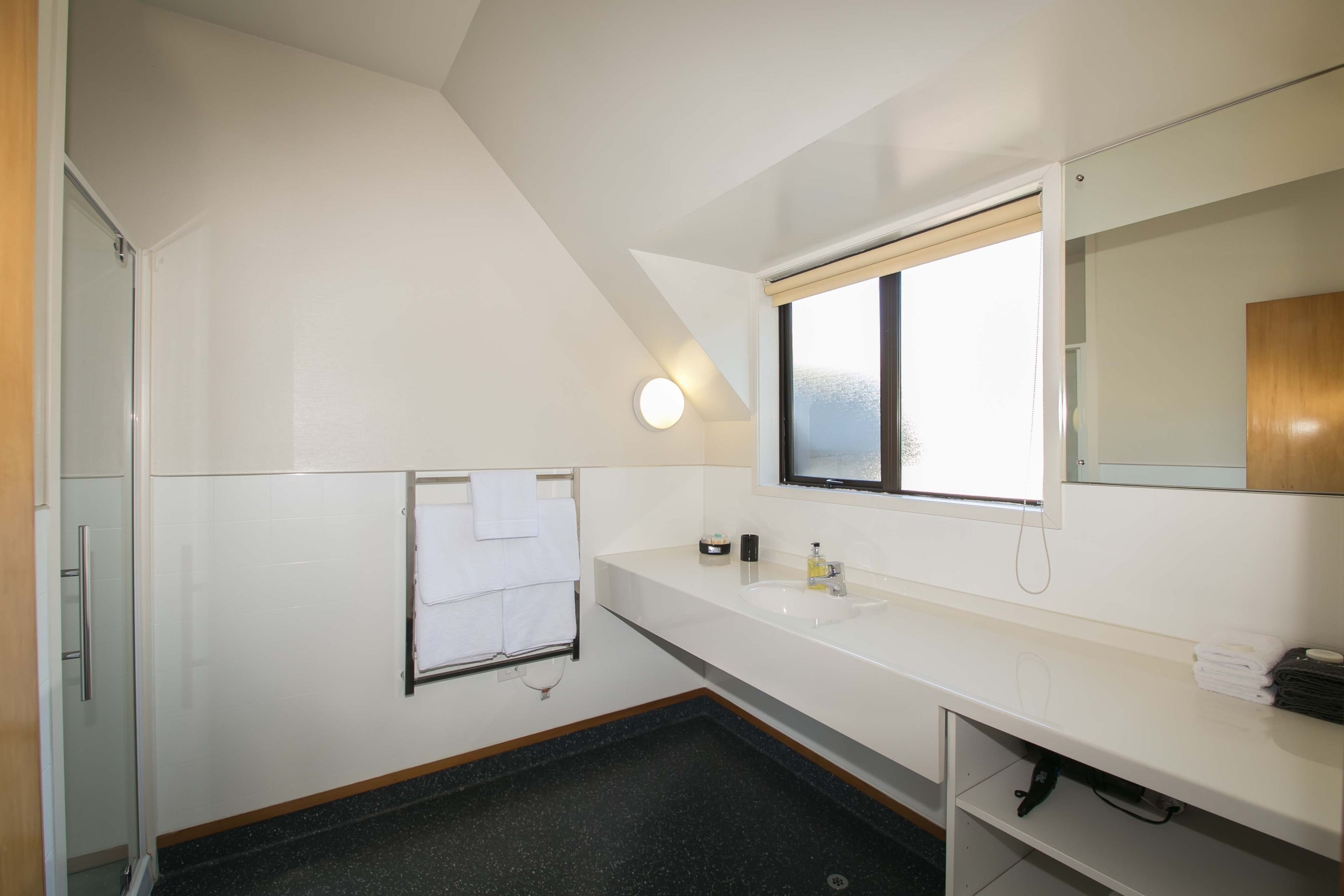 Un baño moderno con lavamanos, espejo y toallero blancos.