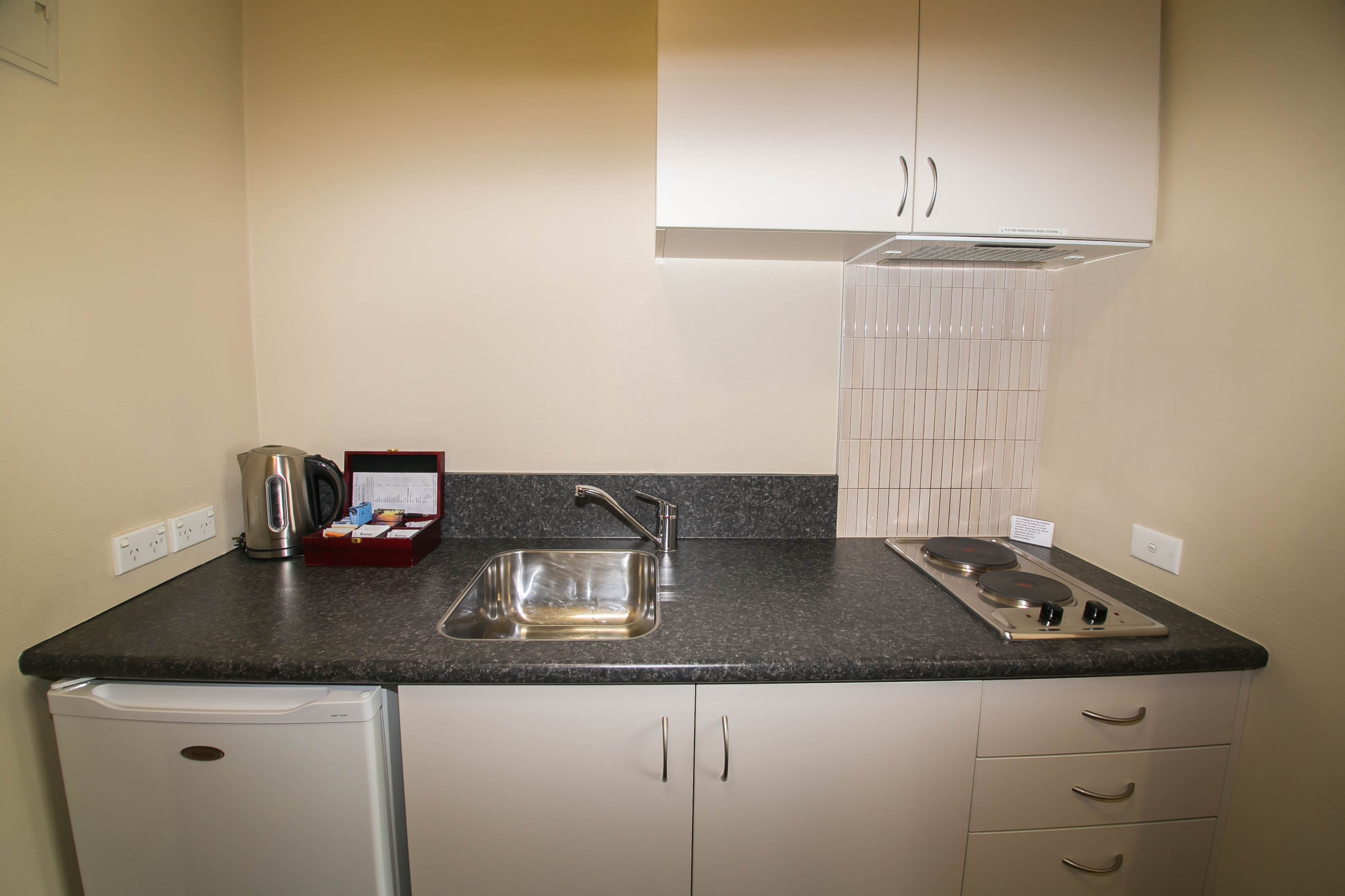 A compact kitchen with a sink, stove, and a small refrigerator.
