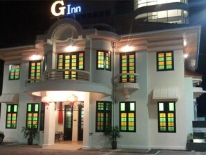 A G Inn hotel with multiple balconies, large windows with green frames, and a central entrance with a red curtain. - G-Inn (George Town)