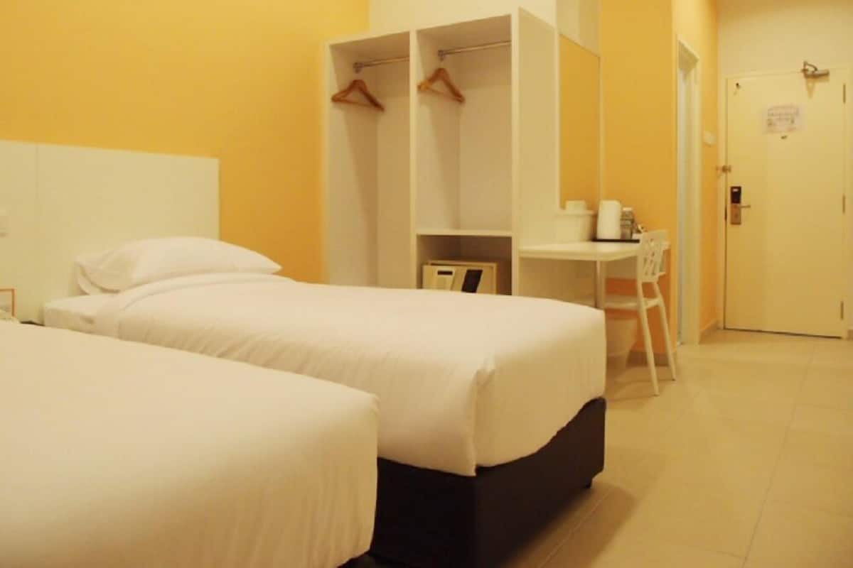 A hotel room with two beds, a desk, and a wardrobe.