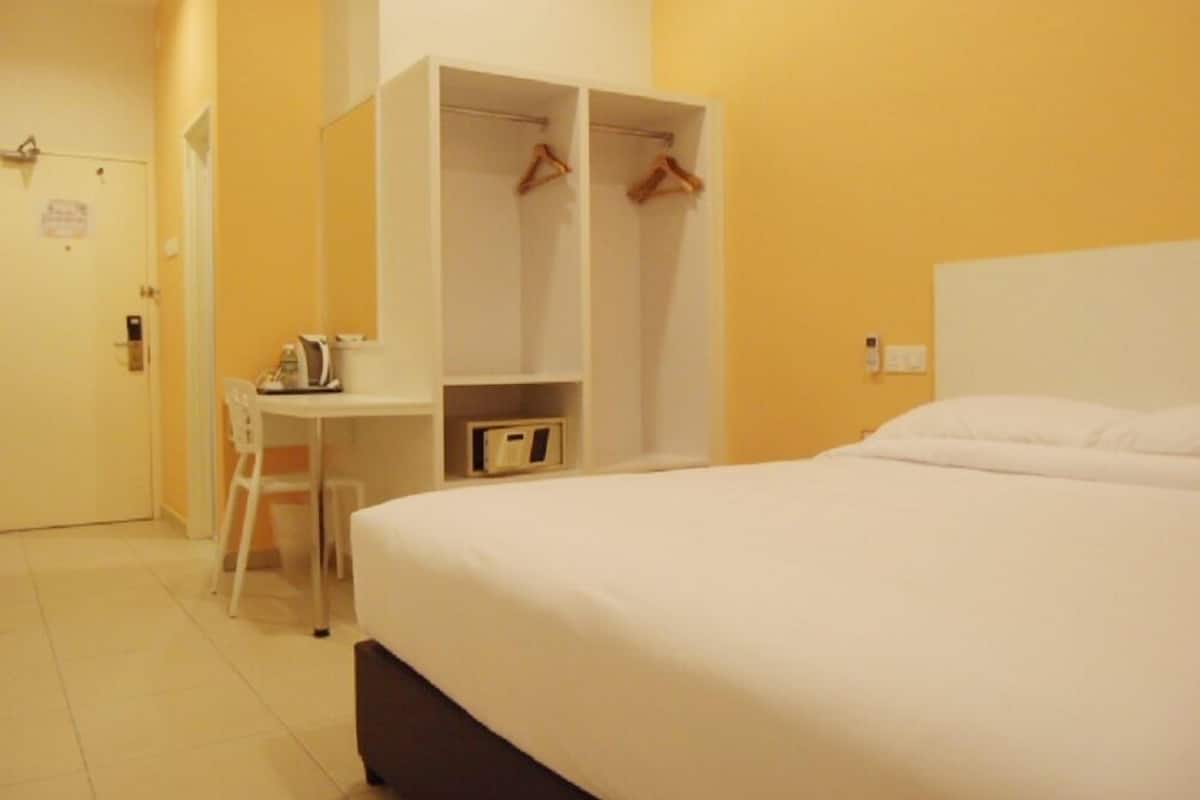 A hotel room with a bed, a desk, and a wardrobe.