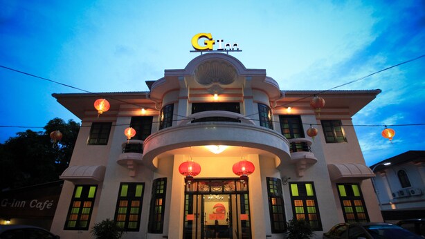 A G-Inn hotel with a curved facade, large windows, and traditional lanterns. - G-Inn (George Town)