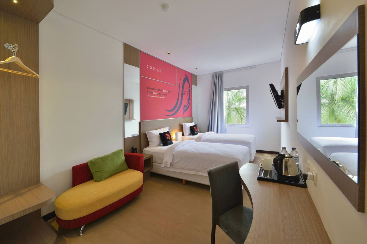 Una habitación de hotel con cama, sofá, escritorio con bandeja y un ventanal grande.