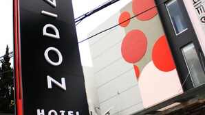 Een hotelschilt met de naam 'ZODIAK HOTEL' en een logo.