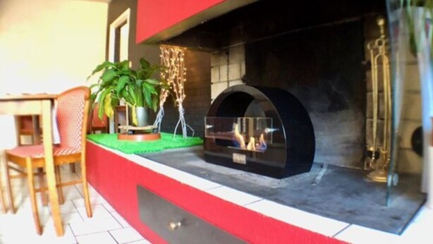 A modern outdoor seating area with a built-in grill and a potted plant. - Hotel Les Cordeliers (Casteljaloux)