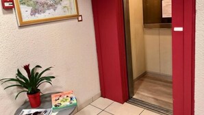 A hotel lobby with a map on the wall, a potted plant, and a children's book on a table. - Hotel Les Cordeliers (Casteljaloux)