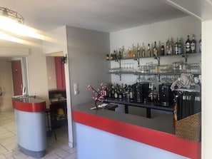 Un espace bar avec des étagères remplies de bouteilles et de verres, un comptoir et un vase décoratif.