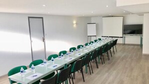 A conference room with a long table, green chairs, and a whiteboard. - Hotel Les Cordeliers (Casteljaloux)