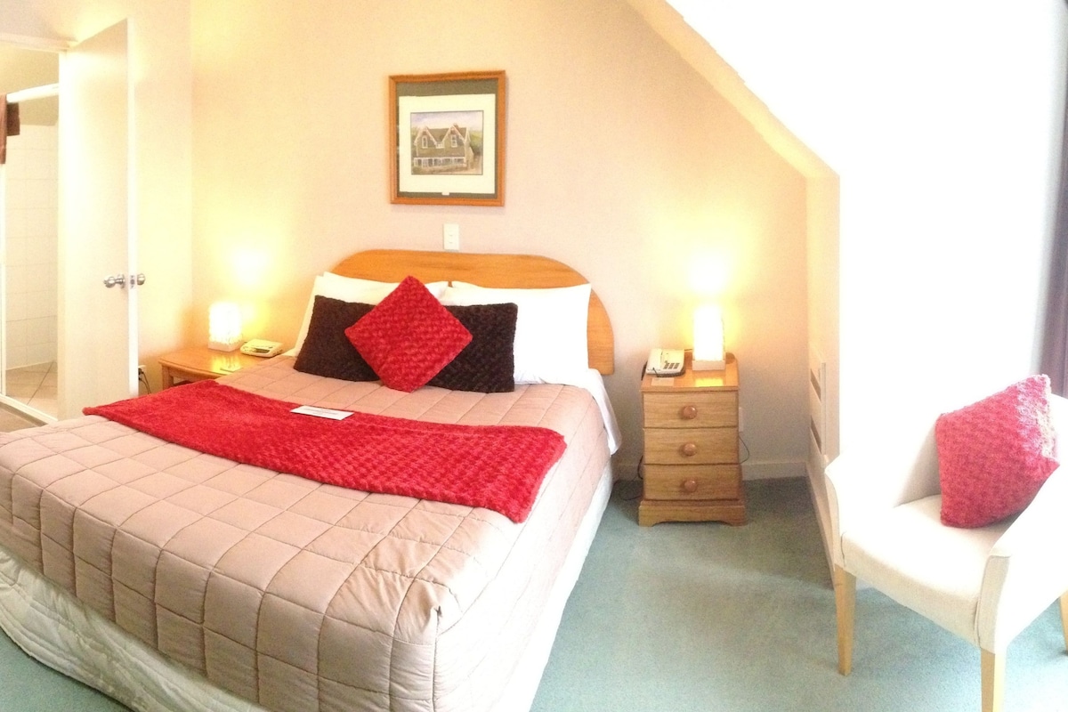 A bedroom with a bed, bedside tables, a chair, and a framed picture on the wall.
