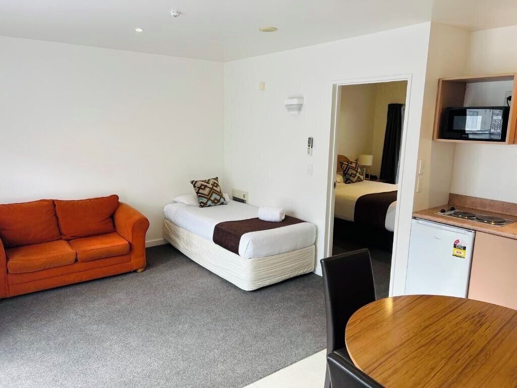 Ein kleines Hotelzimmer mit Schlafgelegenheit, Sofa, einer Küchenzeile und einem Essbereich.