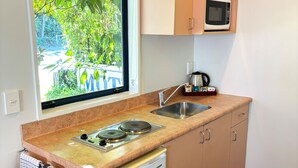 A compact kitchen with a built-in microwave, a sink, and a small refrigerator.