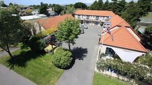 A two-story building with a red-tiled roof, a parking lot, and a small garden area.