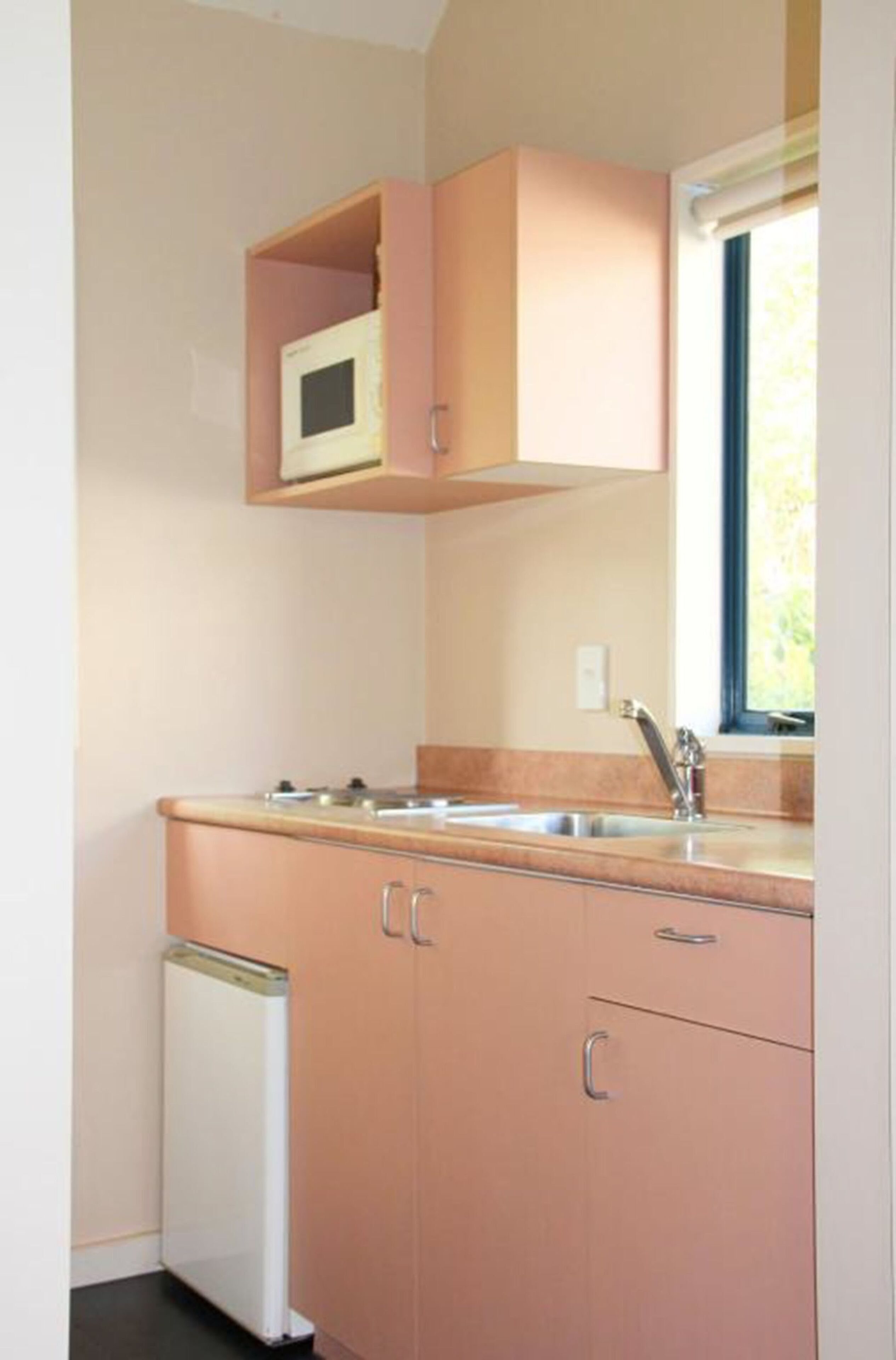 A compact kitchen with a built-in microwave, a sink, and a compact refrigerator.