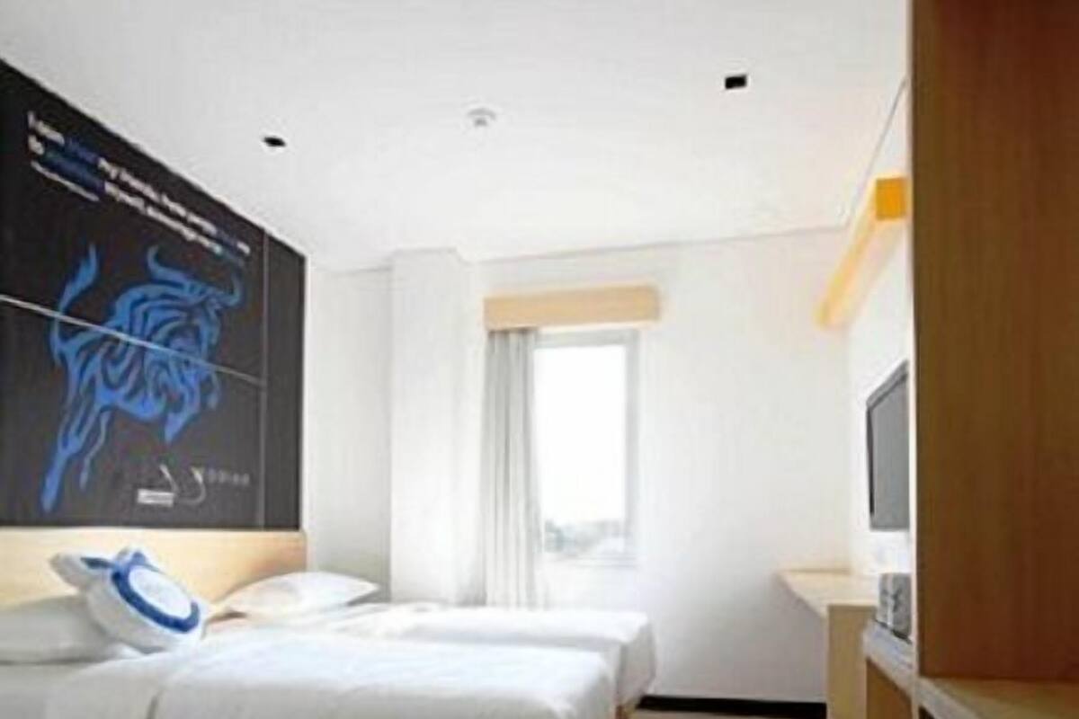 Ett modernt hotellrum med en stor säng, en platt-TV, ett träskåp och ett stort fönster.