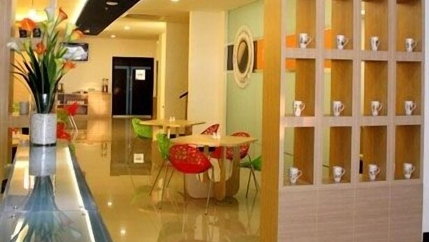 A modern hotel lobby with a reception desk, a seating area with colorful chairs, and a display of decorative items. - Zodiak Paskal by KAGUM Hotels (Bandung)