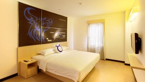 A hotel room with a large bed, a bedside table with a lamp, a wall-mounted TV, and a window with curtains. - Zodiak Paskal by KAGUM Hotels (Bandung)