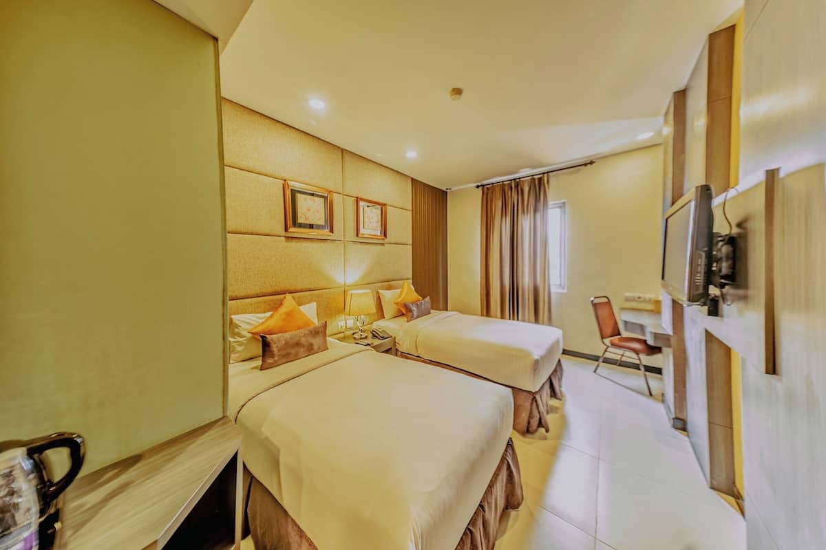 A hotel room with two beds, a desk, a chair, and a television.