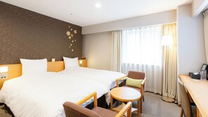 Una habitación de hotel con una cama grande, un escritorio, una silla y una mesita.