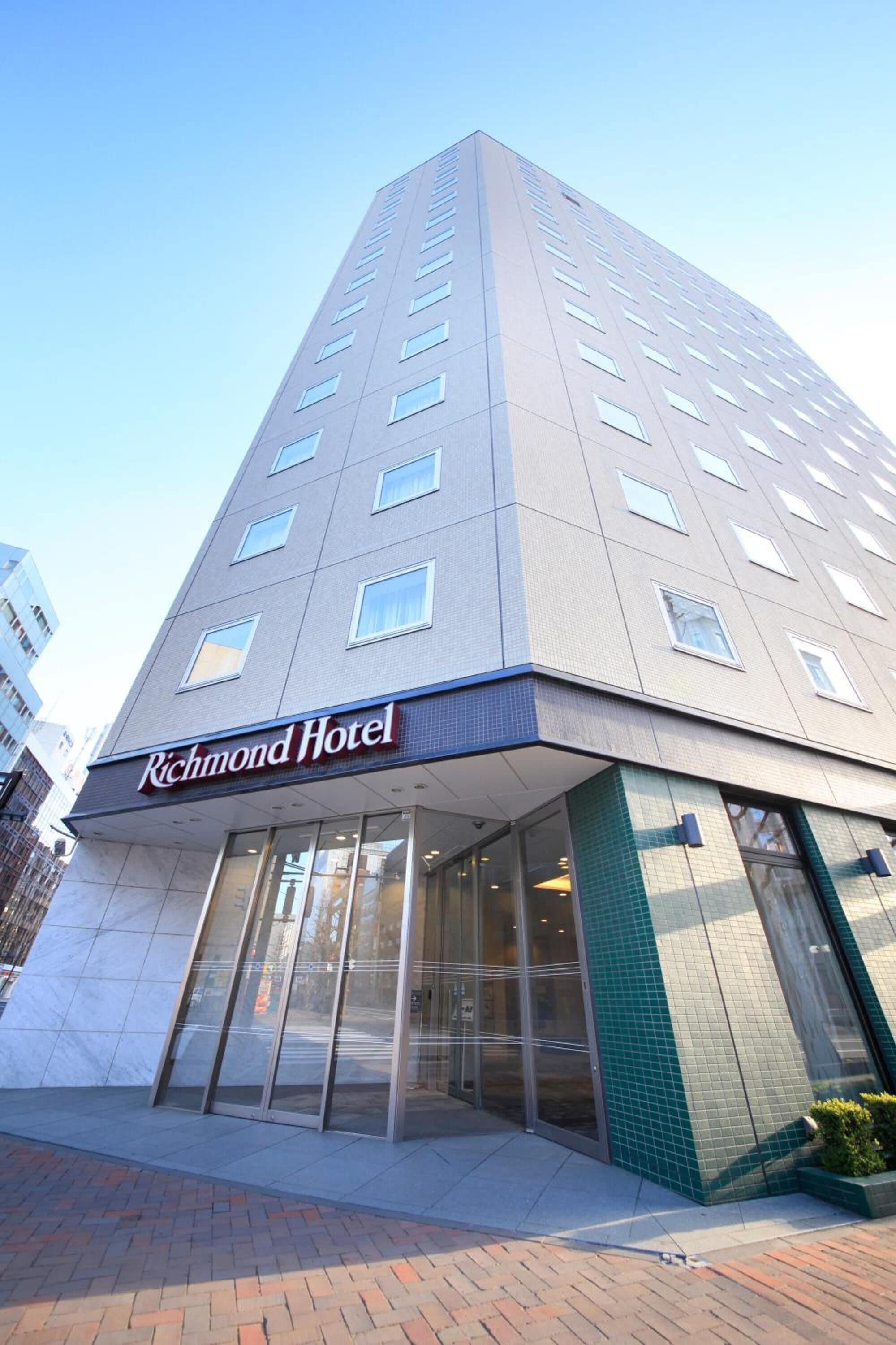 A tall hotel building with a modern design, featuring a prominent "Richmond Hotel" sign at the entrance.