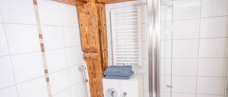 A bathroom with a bathtub, shower, and a wooden ceiling.