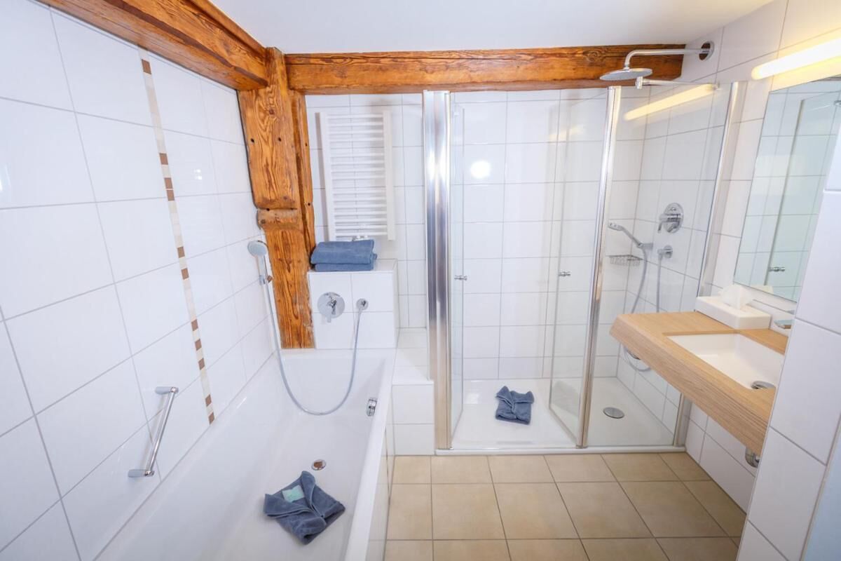 Ein modernes Badezimmer mit einer begehbaren Glasdusche, einer Badewanne und einem Waschtisch mit Spiegel.