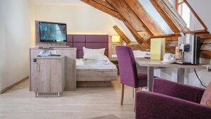 Une pièce confortable avec un lit, un bureau, une chaise, un téléviseur et un plafond en bois.