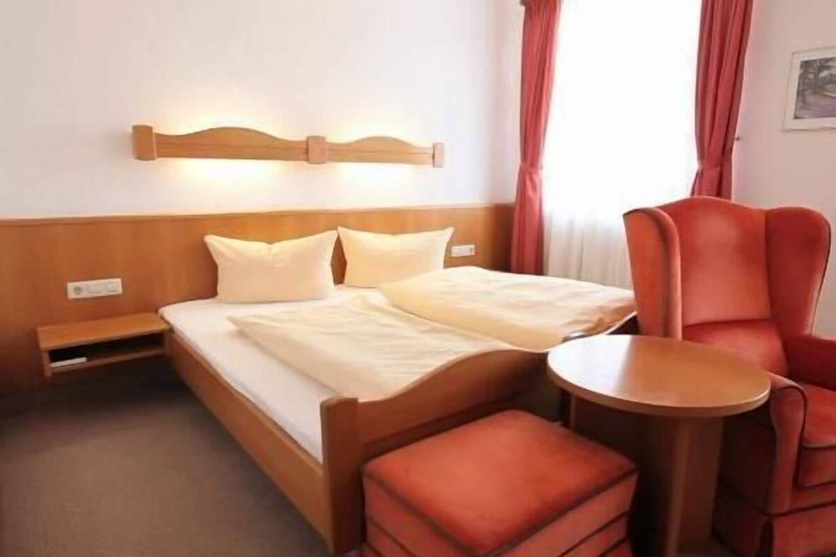Ein Hotelzimmer mit einem Bett, einem kleinen Tisch, einem Stuhl und einer Bank.