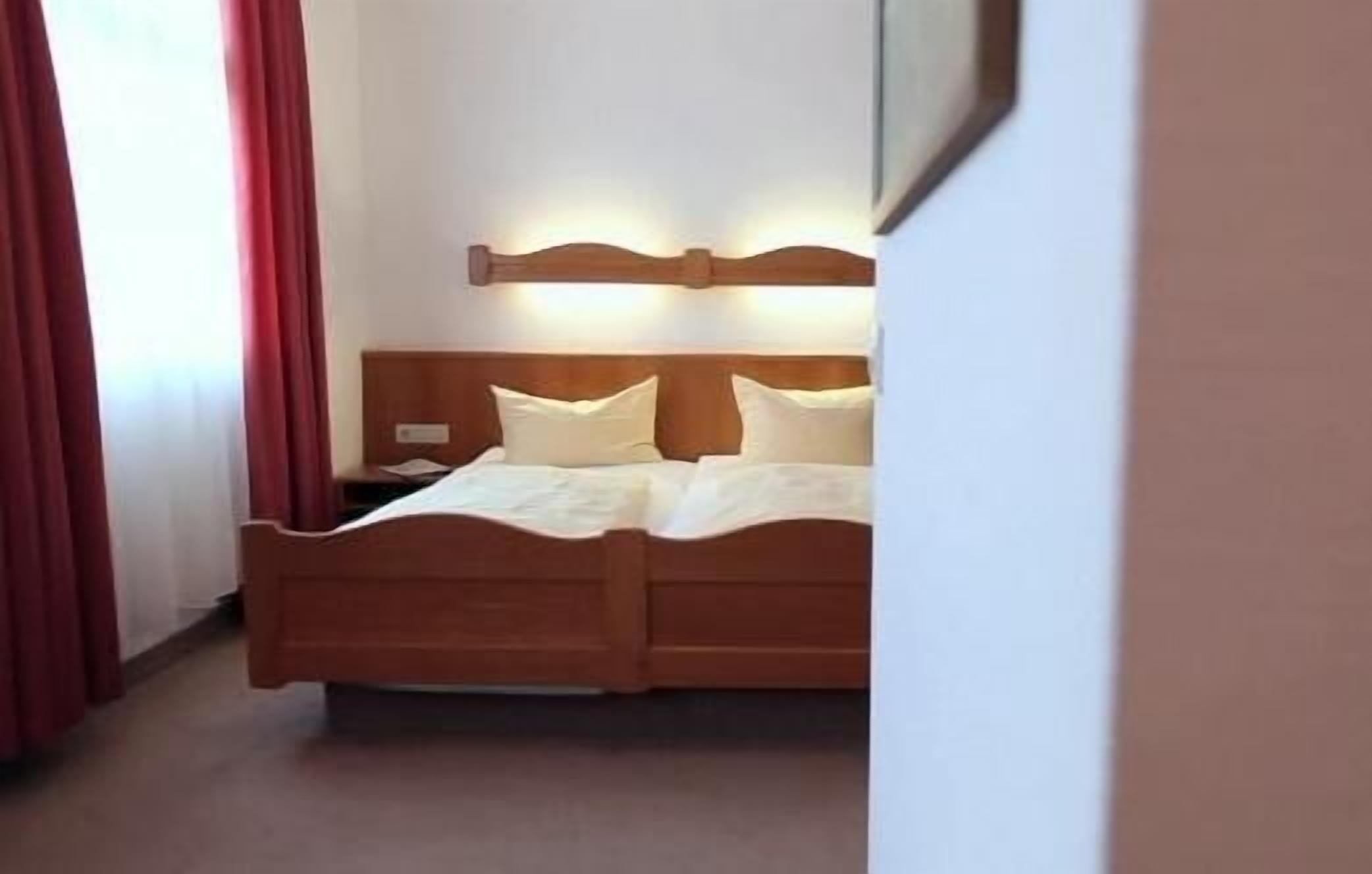 Una habitación de hotel con una cama de madera, ropa de cama blanca y una mesita de noche.