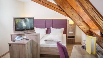 Una camera d'albergo con un letto, una televisione, una scrivania con un telefono e un tavolino con una sedia.