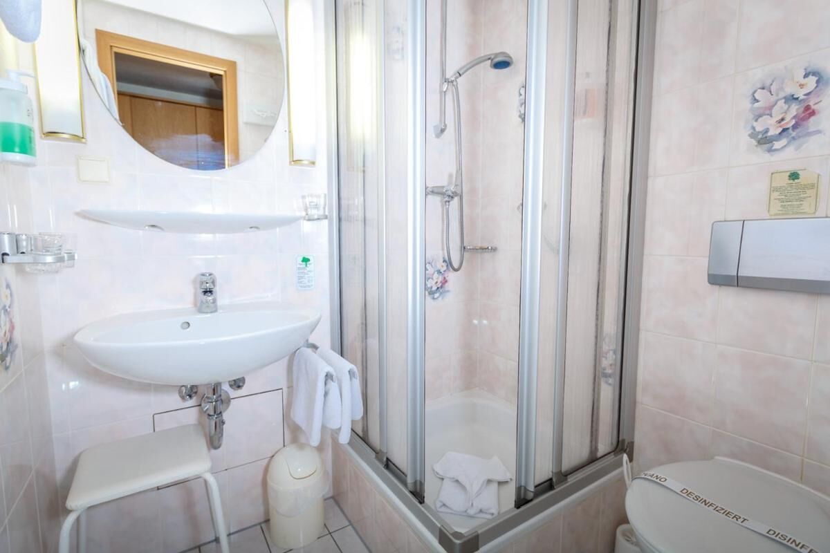 A bathroom with a sink, a shower enclosure, and a toilet.