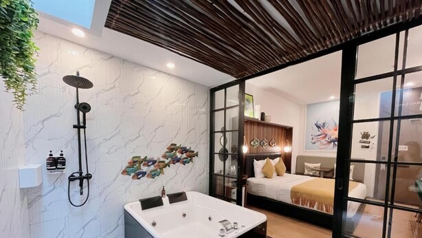 A modern bathroom with a large bathtub, a shower, and a glass door leading to a bedroom. - Oak Tree Urban Jakarta (Jakarta)