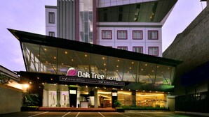 A modern hotel with a unique angular architecture, featuring a prominent glass facade and a sign for Oak Tree Hotel by Verse Hotels. - Oak Tree Urban Jakarta (Jakarta)