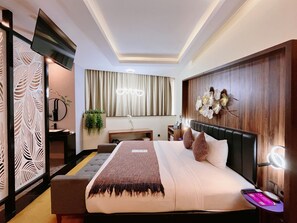 A modern hotel room with a large bed, a desk, a chair, a TV, and a decorative wall. - Oak Tree Urban Jakarta (Jakarta)