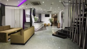 A modern lobby with a reception desk, seating area, and a staircase. - Oak Tree Urban Jakarta (Jakarta)