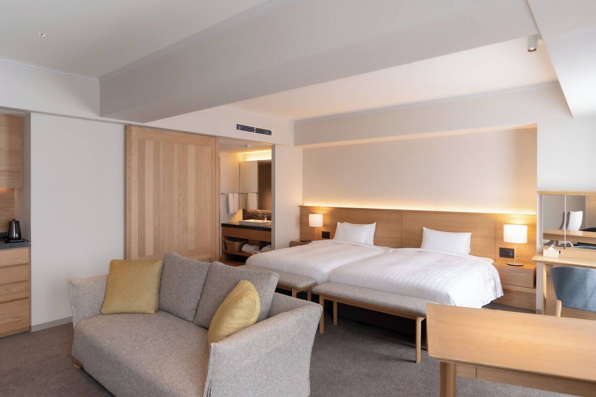 Quarto de hotel com uma cama grande, um sofá, uma escrivaninha e um espelho.