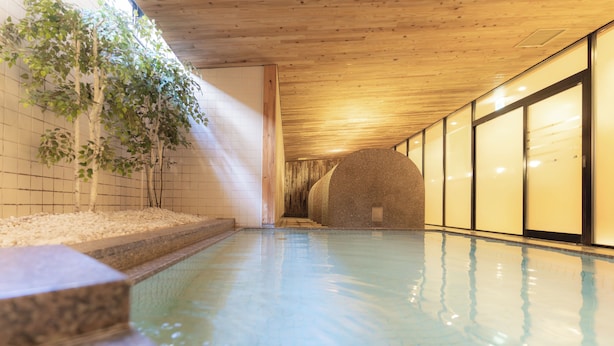 Una piscina con suelo de baldosas, techo de madera y una pared con un ventanal grande.