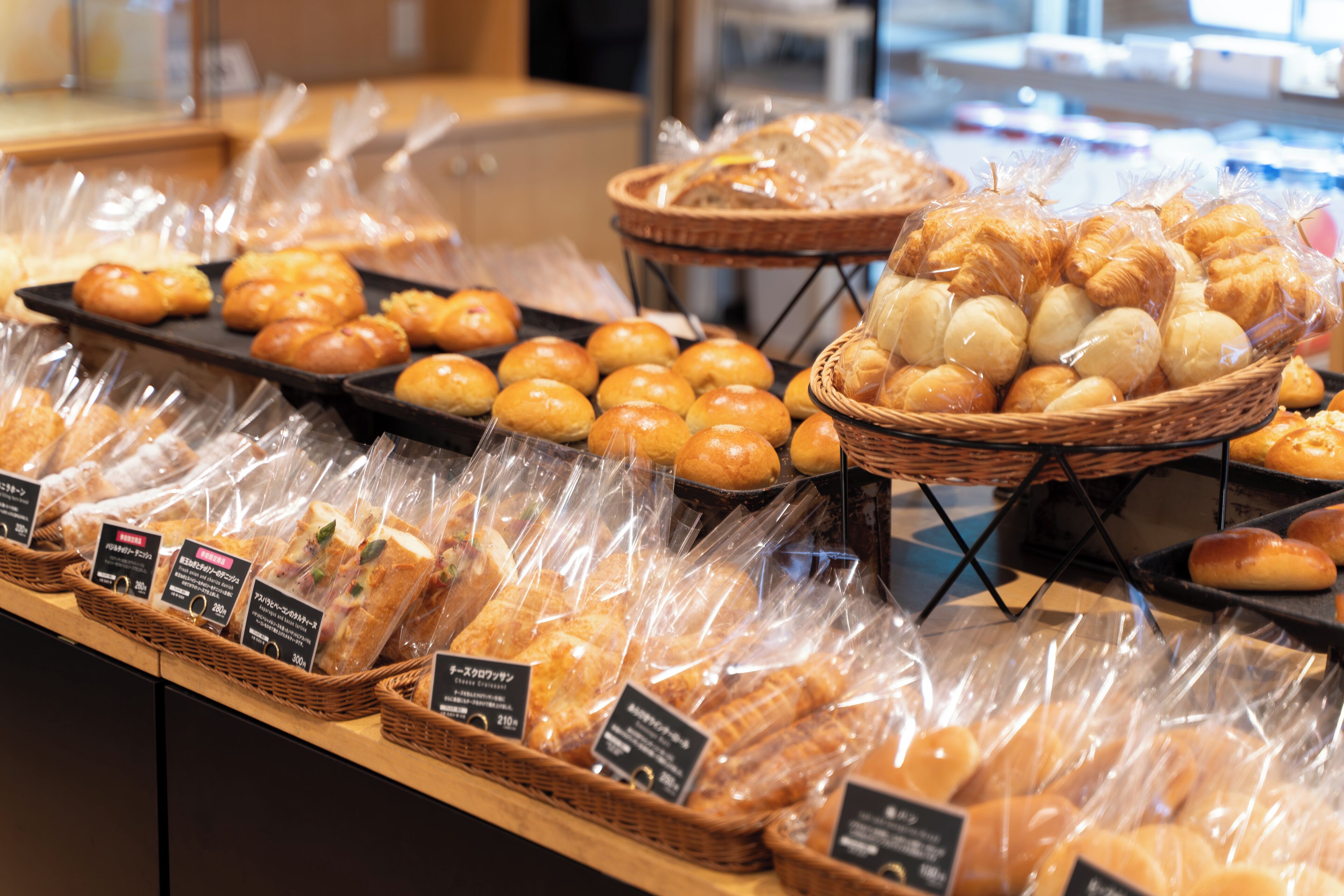 A bakery display with various breads and pastries in baskets and plastic packaging.